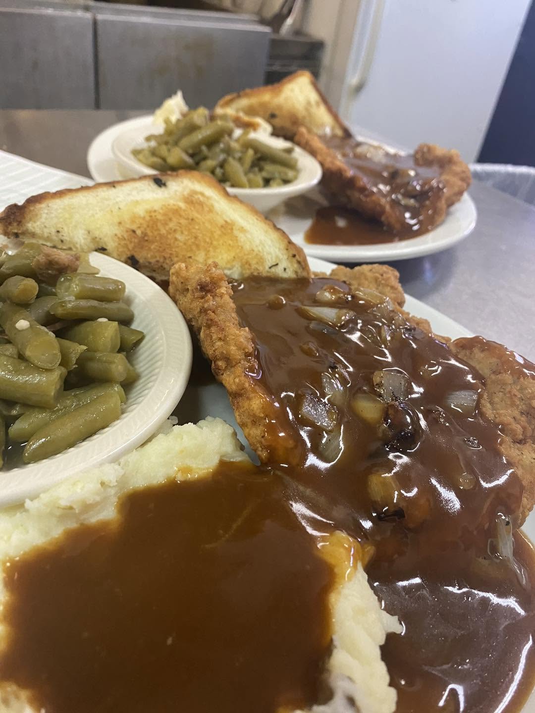 Country fried steak plate with gravy, mashed potatoes and green beans